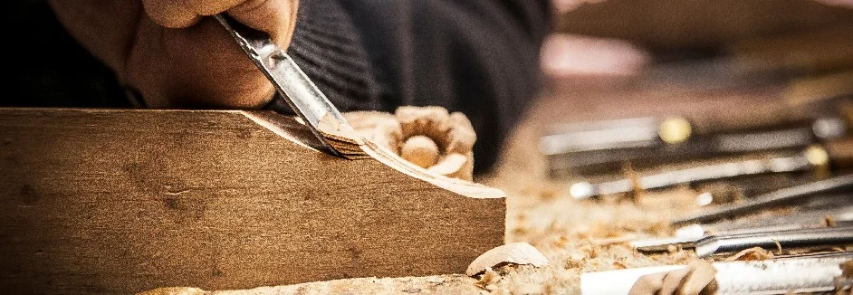 Person schnitzt Holz mit einem Stechbeitel